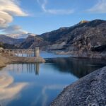 A mountain reservoir and dam holding back water in a foothills valley
