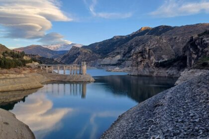 A mountain reservoir and dam holding back water in a foothills valley
