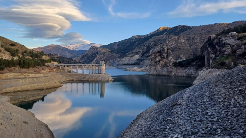 A mountain reservoir and dam holding back water in a foothills valley