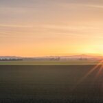 Prairie farmland under an orange sunset sky