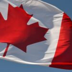 A Canadian flag flying against a blue sky