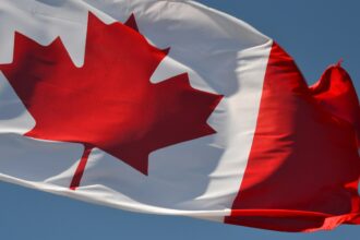 A Canadian flag flying against a blue sky