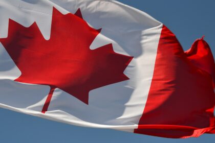 A Canadian flag flying against a blue sky