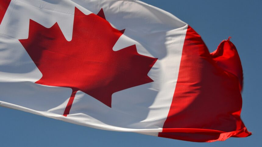 A Canadian flag flying against a blue sky
