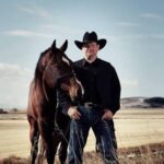 Scott Hardy standing with a horse in the Alberta foothills near Longview