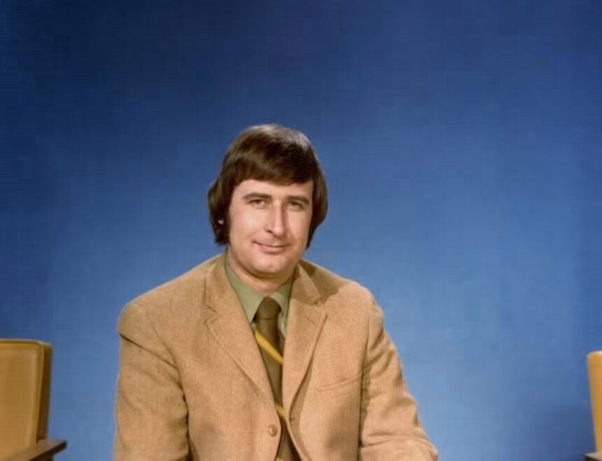 Ralph Klein in a studio portrait from his years as a Calgary television reporter, tan jacket against a blue backdrop