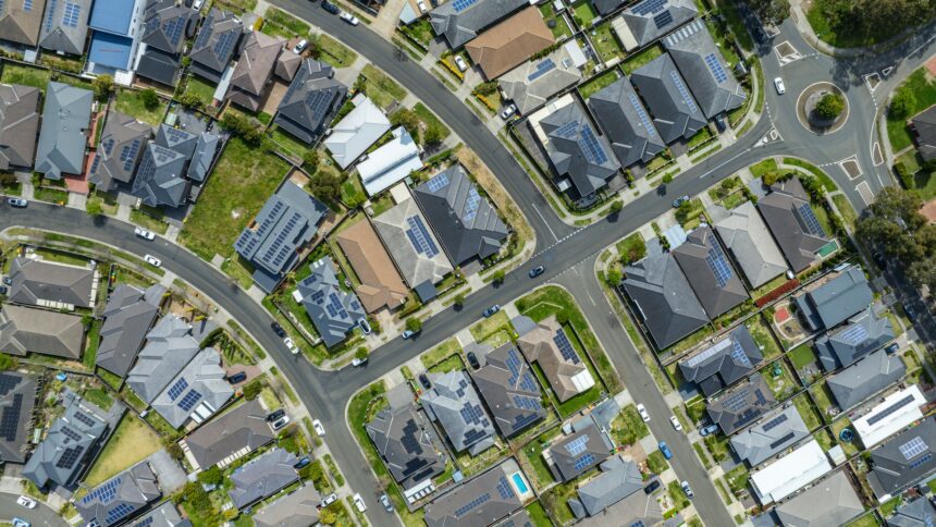 Aerial view of a suburban neighbourhood where many house roofs carry solar panels