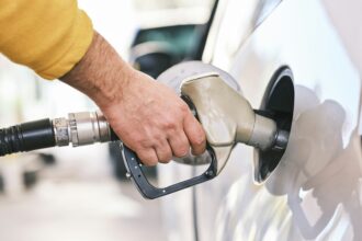 A hand holding a fuel nozzle in a vehicle filler neck