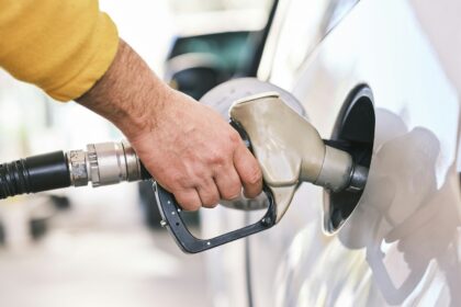 A hand holding a fuel nozzle in a vehicle filler neck