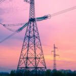 High voltage transmission towers crossing open country at dusk