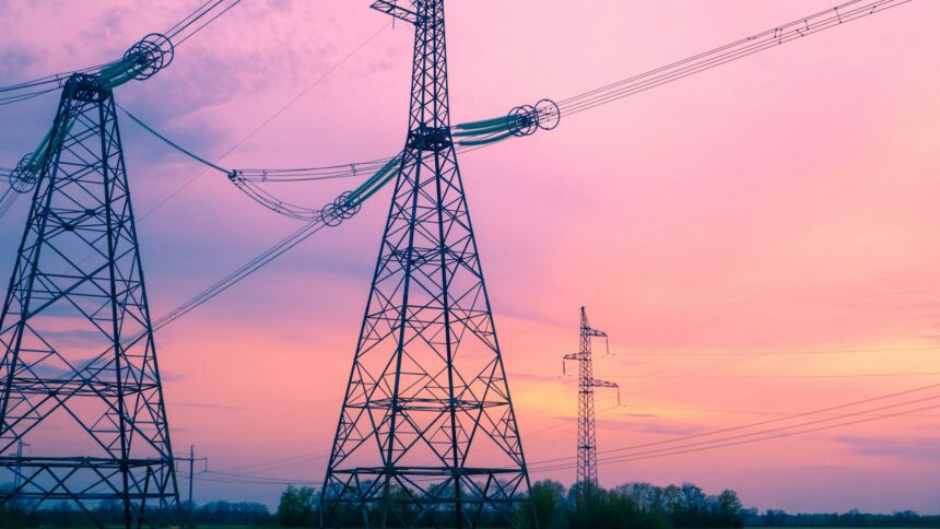 High voltage transmission towers crossing open country at dusk