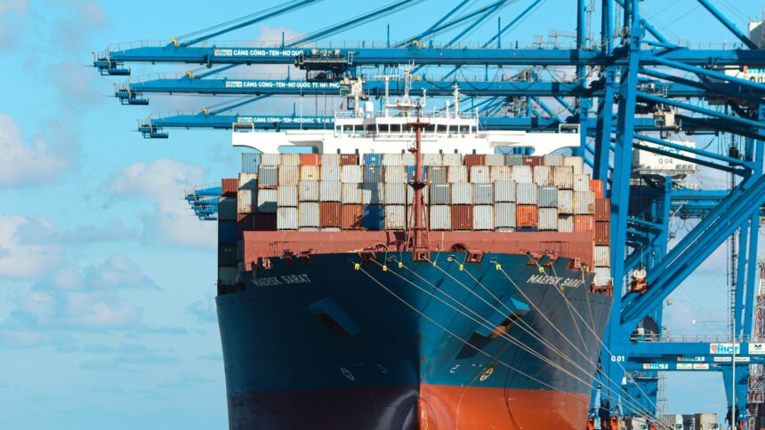 Shipping containers stacked beside gantry cranes at a port