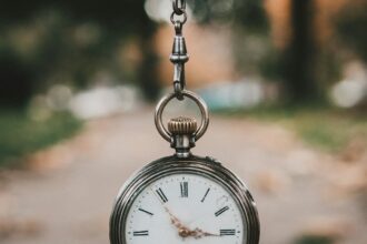 An antique railway pocket watch resting on a weathered surface