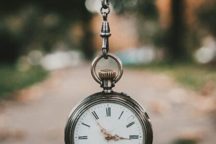 An antique railway pocket watch resting on a weathered surface