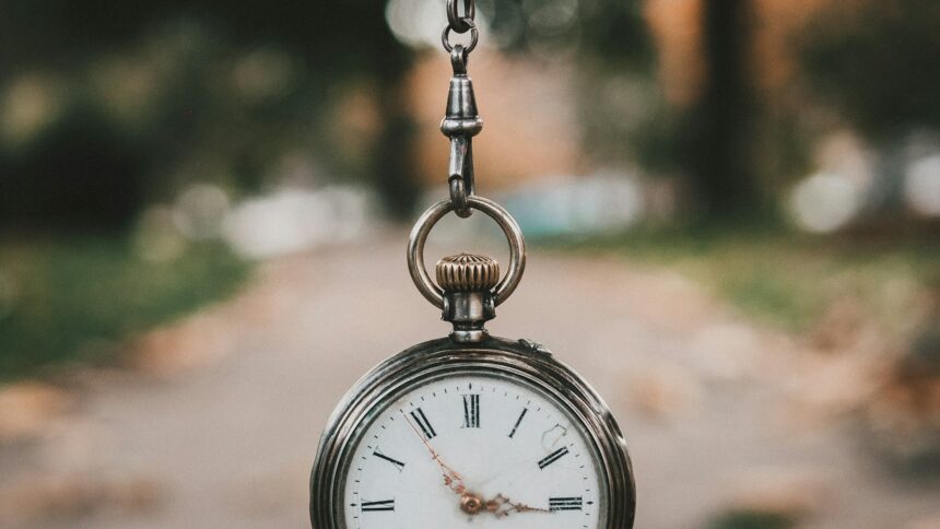 An antique railway pocket watch resting on a weathered surface