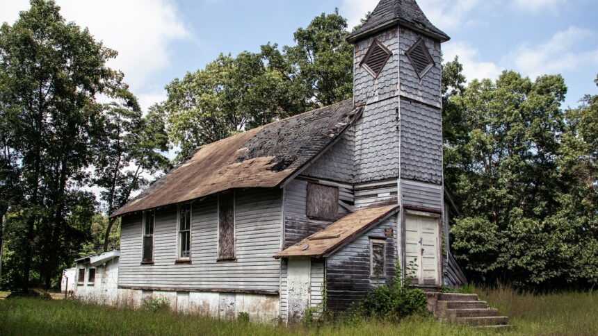 A small white wooden country church standing among trees