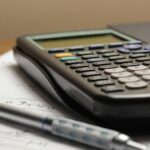 A calculator and pen on a business ledger sheet