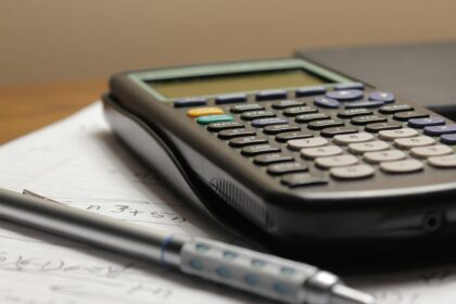 A calculator and pen on a business ledger sheet