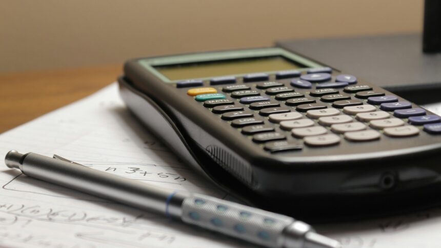 A calculator and pen on a business ledger sheet