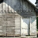 A weathered wood frame building standing alone on open ground