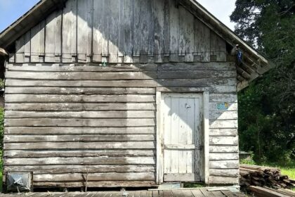 A weathered wood frame building standing alone on open ground