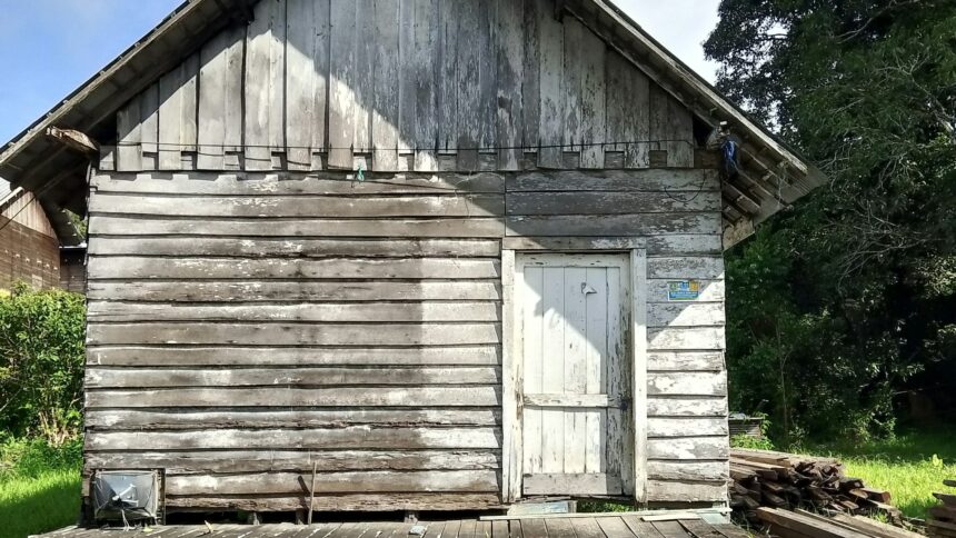 A weathered wood frame building standing alone on open ground