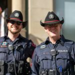 Two uniformed police officers in cowboy hats standing on a city street