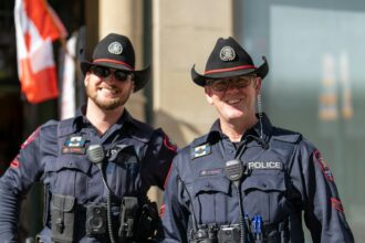 Two uniformed police officers in cowboy hats standing on a city street