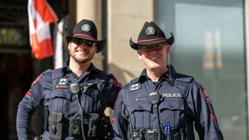 Two uniformed police officers in cowboy hats standing on a city street