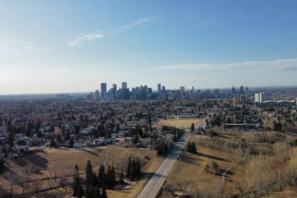 An aerial view across Calgary neighbourhoods toward the downtown skyline