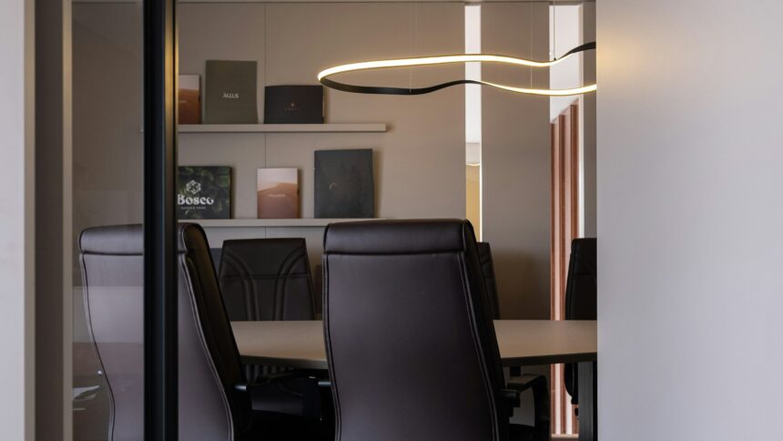 A modern conference room with a long table and leather chairs