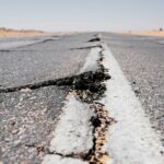 A deep crack running across a worn highway and its centre line