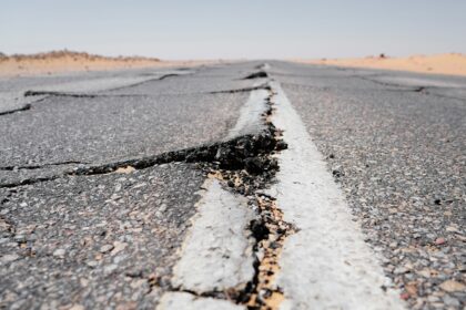 A deep crack running across a worn highway and its centre line
