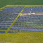 A solar array on farmland beside an industrial site