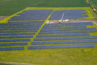 A solar array on farmland beside an industrial site