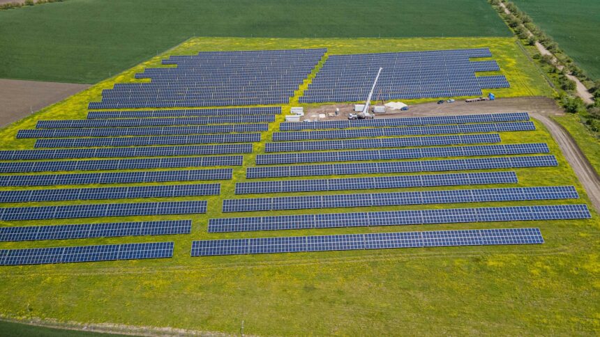A solar array on farmland beside an industrial site