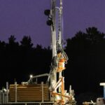 A drilling rig lit up and operating after dark on a well site
