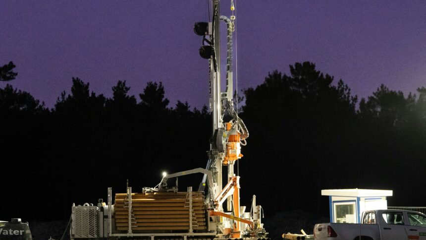 A drilling rig lit up and operating after dark on a well site