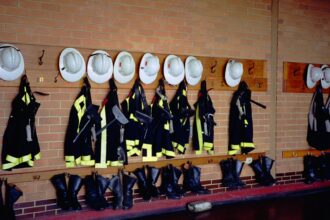 Firefighter turnout gear and helmets hanging on a fire hall wall