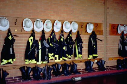 Firefighter turnout gear and helmets hanging on a fire hall wall