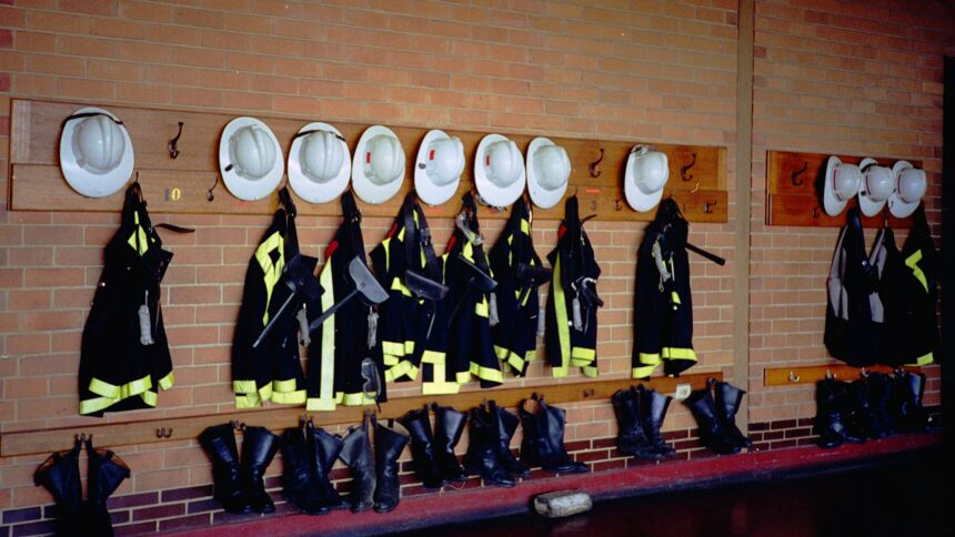Firefighter turnout gear and helmets hanging on a fire hall wall
