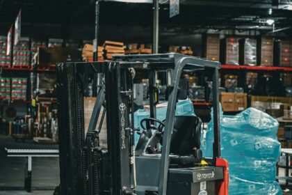 A forklift parked inside a warehouse stacked with palletised goods