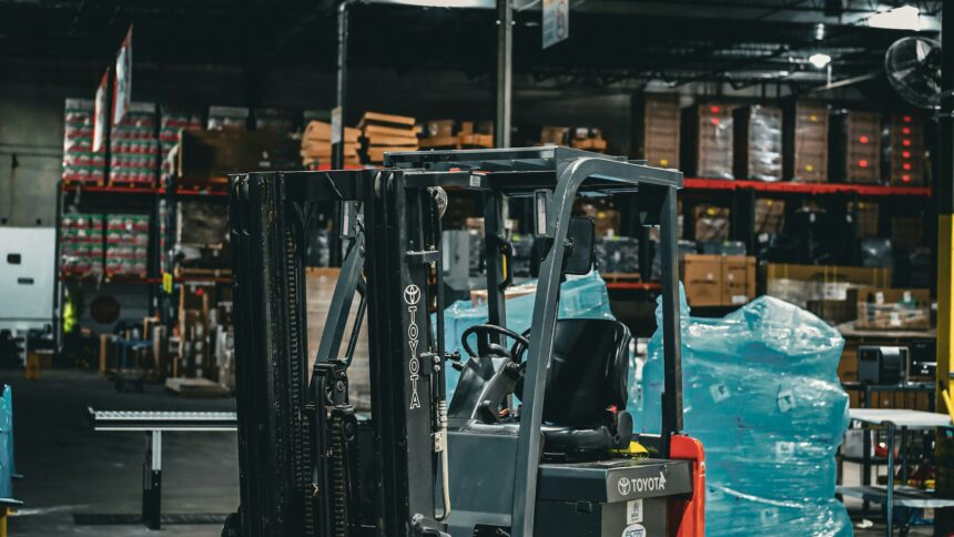 A forklift parked inside a warehouse stacked with palletised goods