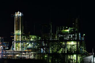 A gas processing complex with towers and piping lit up at night