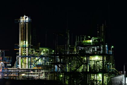A gas processing complex with towers and piping lit up at night