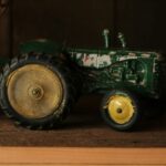 A green toy tractor standing on a wooden shelf