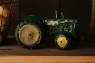 A green toy tractor standing on a wooden shelf