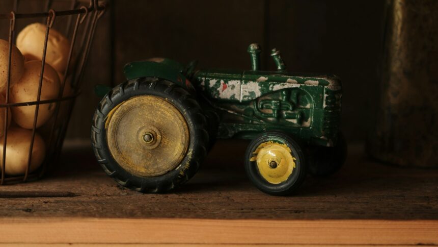 A green toy tractor standing on a wooden shelf