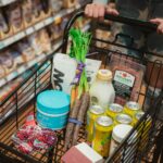 A shopper pushing a cart full of groceries down a store aisle