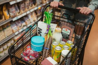 A shopper pushing a cart full of groceries down a store aisle